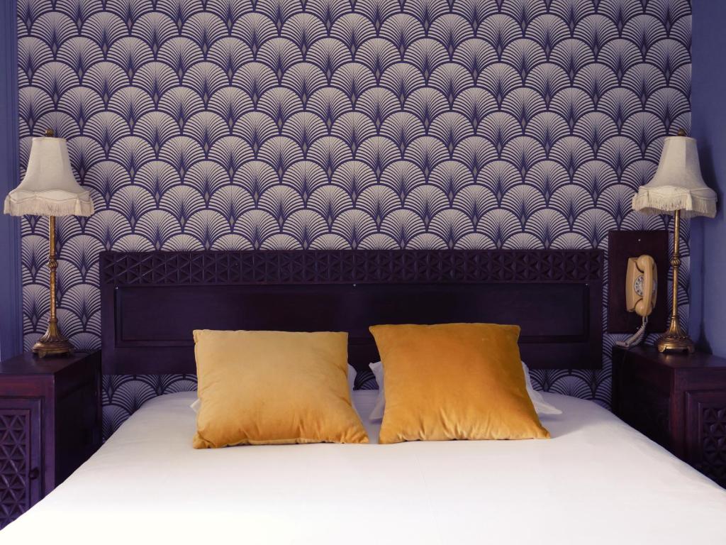 1 cama con 2 almohadas en un dormitorio con pared en Saint Charles Hôtel & Coliving Biarritz, en Biarritz