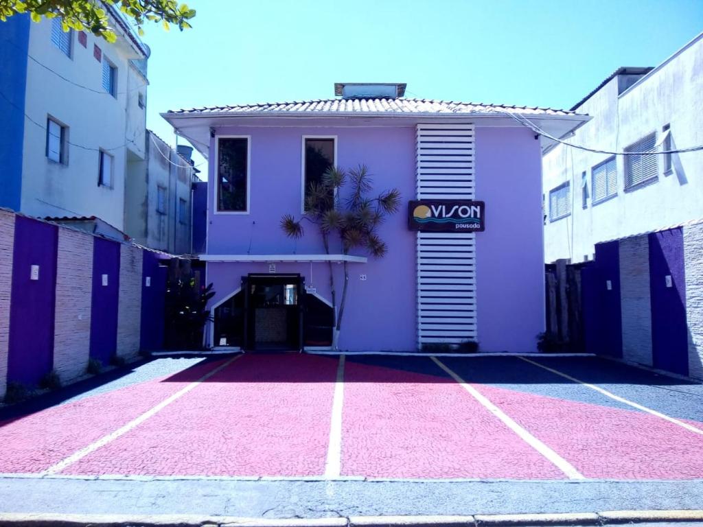 a purple building with a pink parking lot at Pousada Vison in Ubatuba