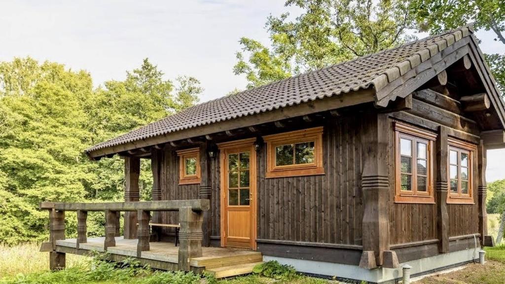 a cabin in the woods with a wooden porch at Jõeääre puhkekeskus in Langa