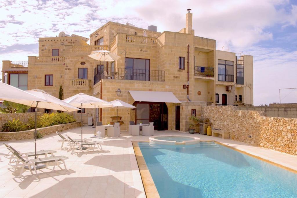 a house with a swimming pool in front of a building at Ferrieha B&B in Qala