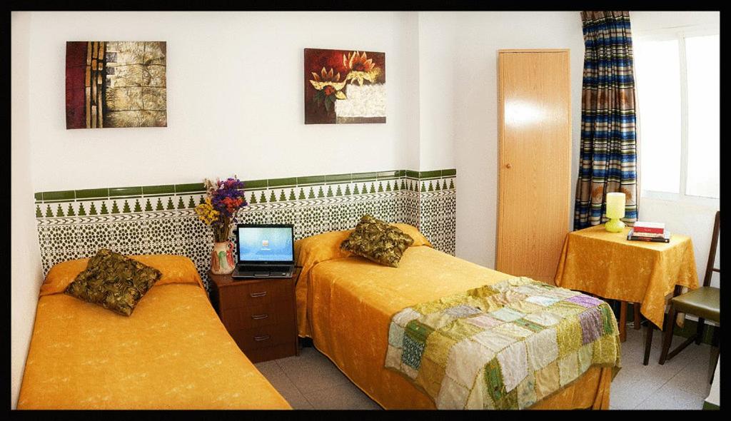 um quarto de hotel com 2 camas e um computador portátil numa secretária em Hostal Estación em Almeria