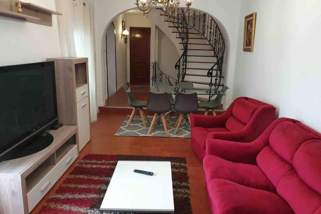 a living room with a red couch and a staircase at Casa da Mina in Ponta Delgada