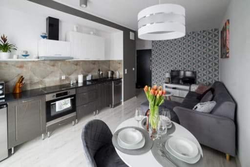 een keuken en een woonkamer met een tafel en stoelen bij APARTAMENT KAMILA in Gdańsk
