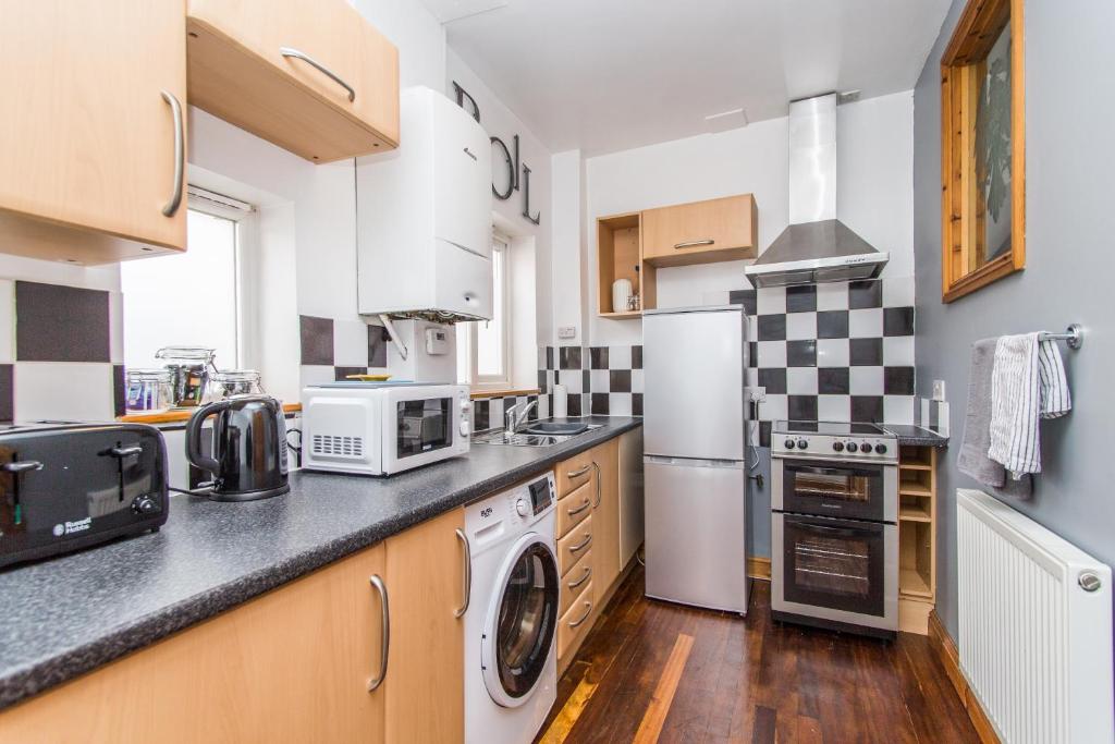 a kitchen with white appliances and wooden cabinets at The Old Dairy Mill Street in Crediton