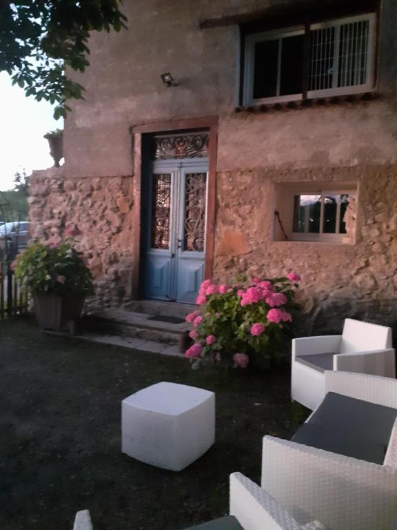 una casa con una puerta azul y algunas flores en Gîte Le Marronnier en Ganac