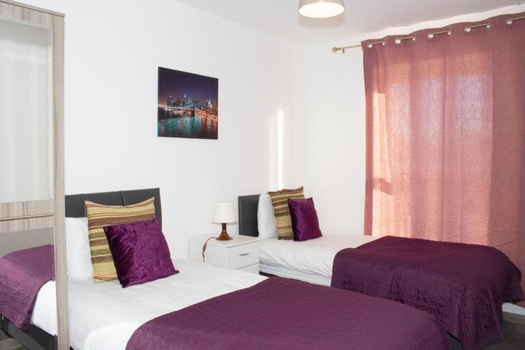 - 2 lits dans une chambre de couleur violette et blanche dans l'établissement TMS Beautiful 2 Bedroom Apartment!Ensuite!Dovestone Lakeside, à West Thurrock