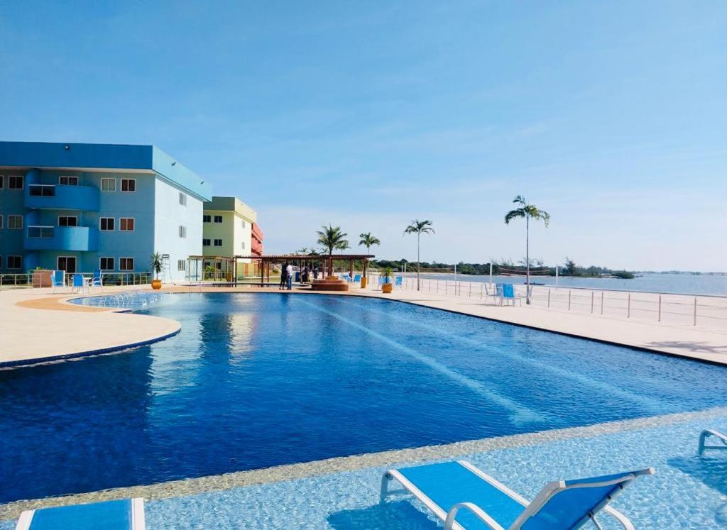 uma piscina com duas espreguiçadeiras e o oceano em Apto Arraial do Cabo - Condomínio Golden Lake em Arraial do Cabo