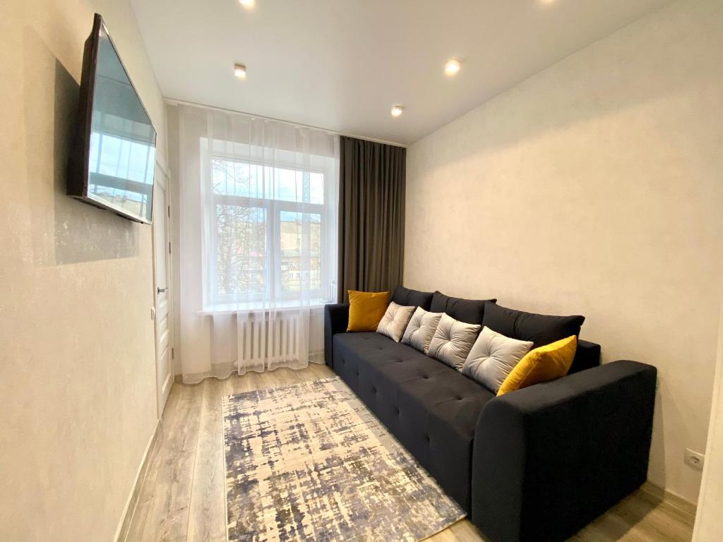 a living room with a black couch and a window at Deribasovskaya Center Apartment in Odesa