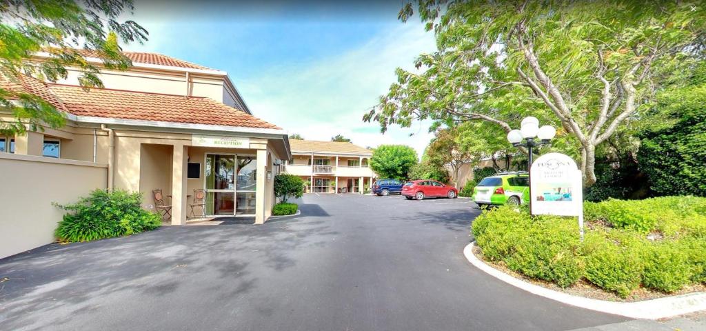 una calle frente a un edificio con coches aparcados en Tuscana Motor Lodge en Christchurch