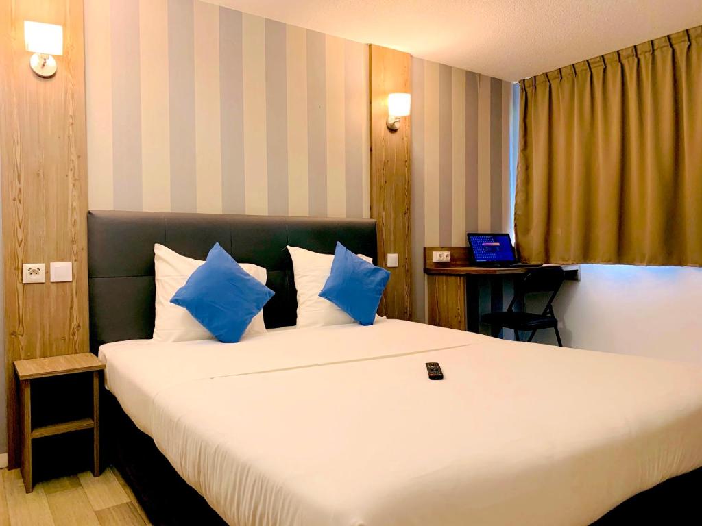a hotel room with a large bed with blue pillows at Hotel RBX - Roubaix Centre in Roubaix