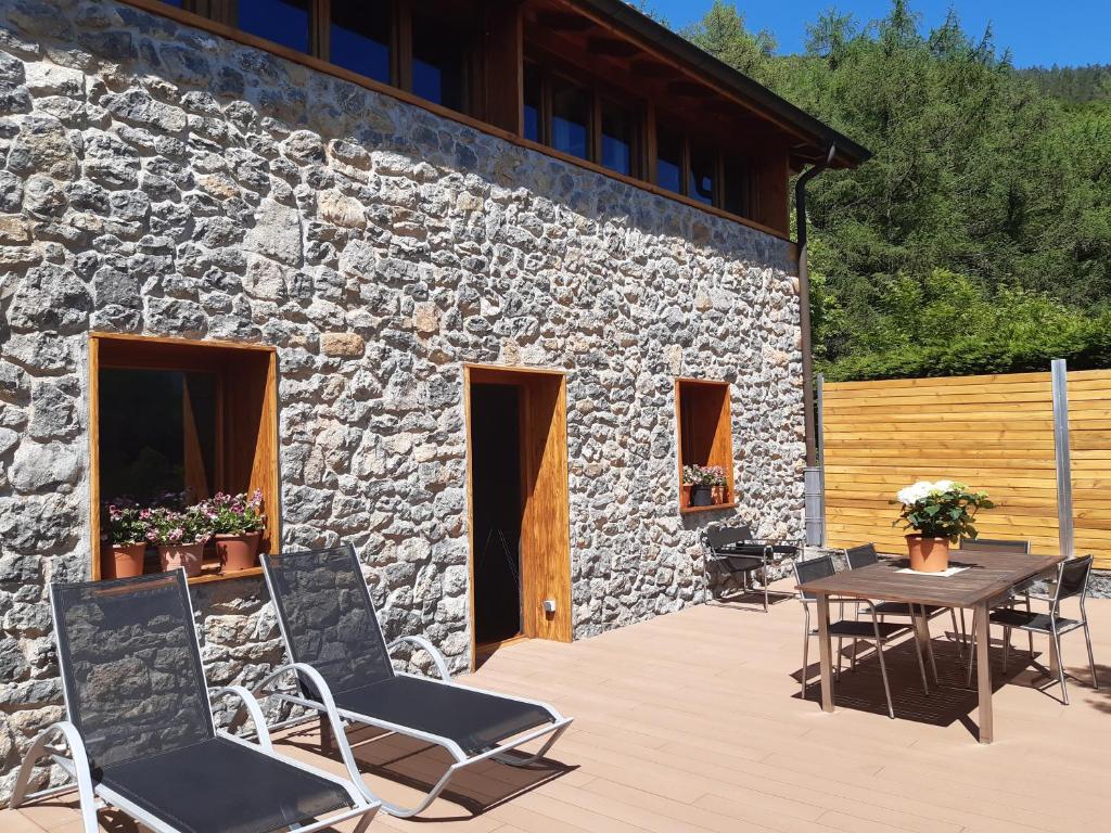 un patio con sillas y una mesa frente a un edificio de piedra en CASA RURAL AINGERU NATURALEZA Y MONTAÑA en Oñate