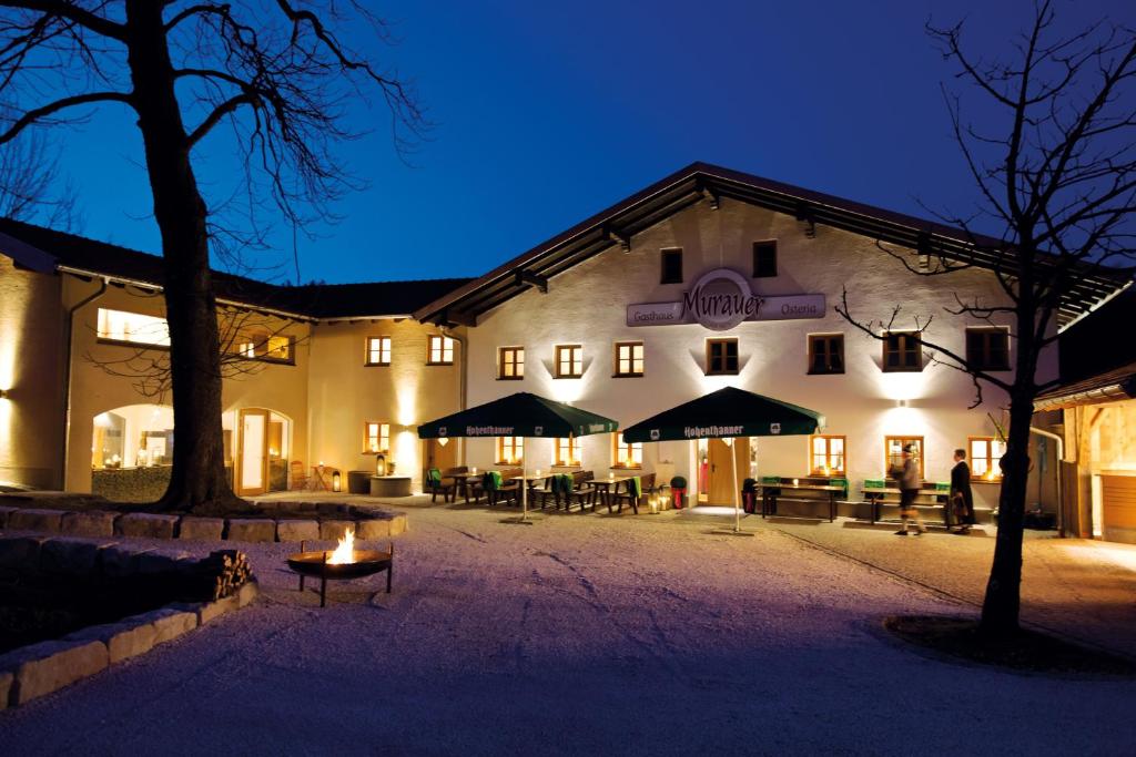 ein beleuchtetes Gebäude mit Tischen und Stühlen in der Nacht in der Unterkunft Gasthaus Murauer in Simbach am Inn