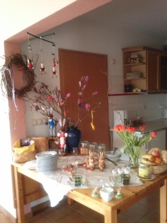 a kitchen counter with a table with plates and flowers at Pension Moritz und Hofladen unterm Storchennest -16303 Schwedt,Schwedter Allee1 in Schwedt