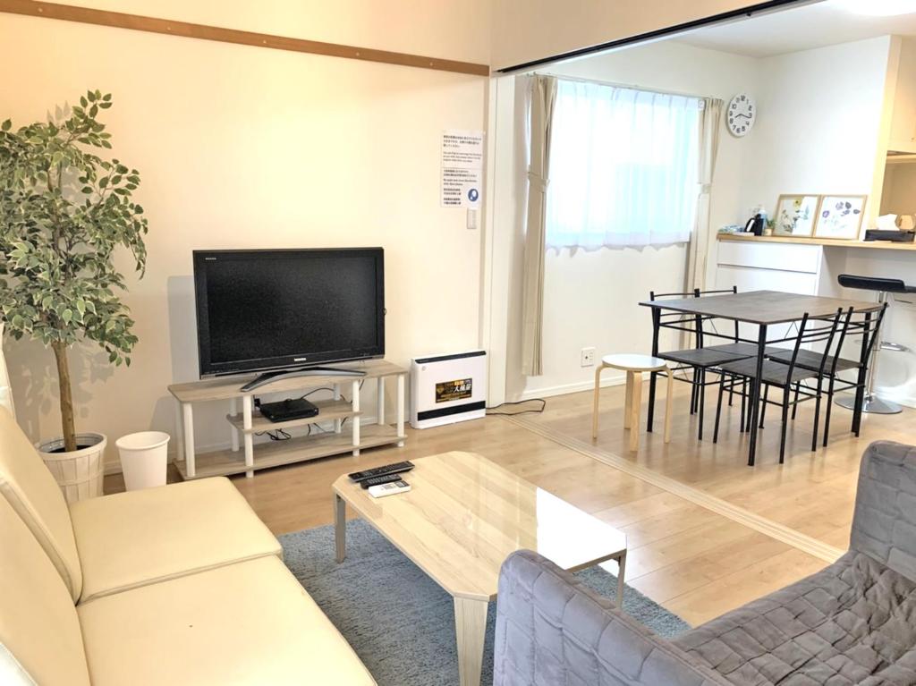ein Wohnzimmer mit einem TV und einem Tisch in der Unterkunft Guesthouse徳島201 in Tokushima