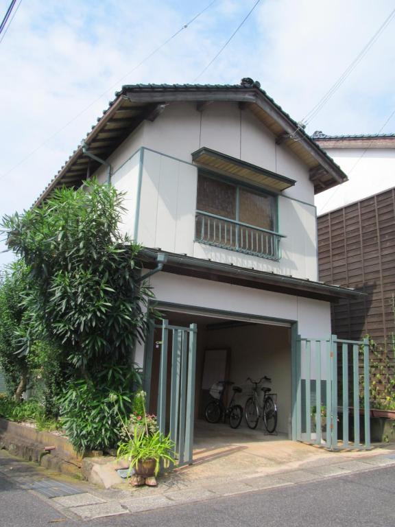 Pavillon Higashi Fujita - an independent house في Moroyose: منزل أبيض مع دراجات متوقفة أمامه