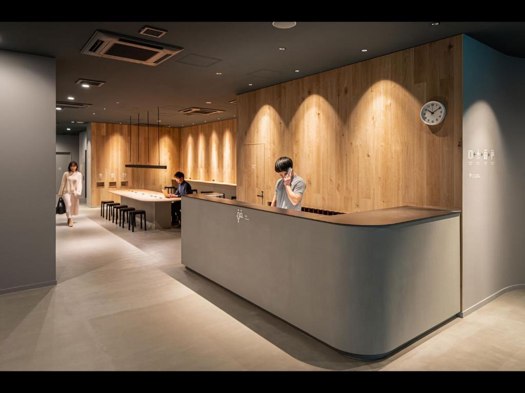 un vestíbulo con gente de pie en un mostrador de recepción en Capsule Plus Yokohama Sauna & Capsule en Yokohama