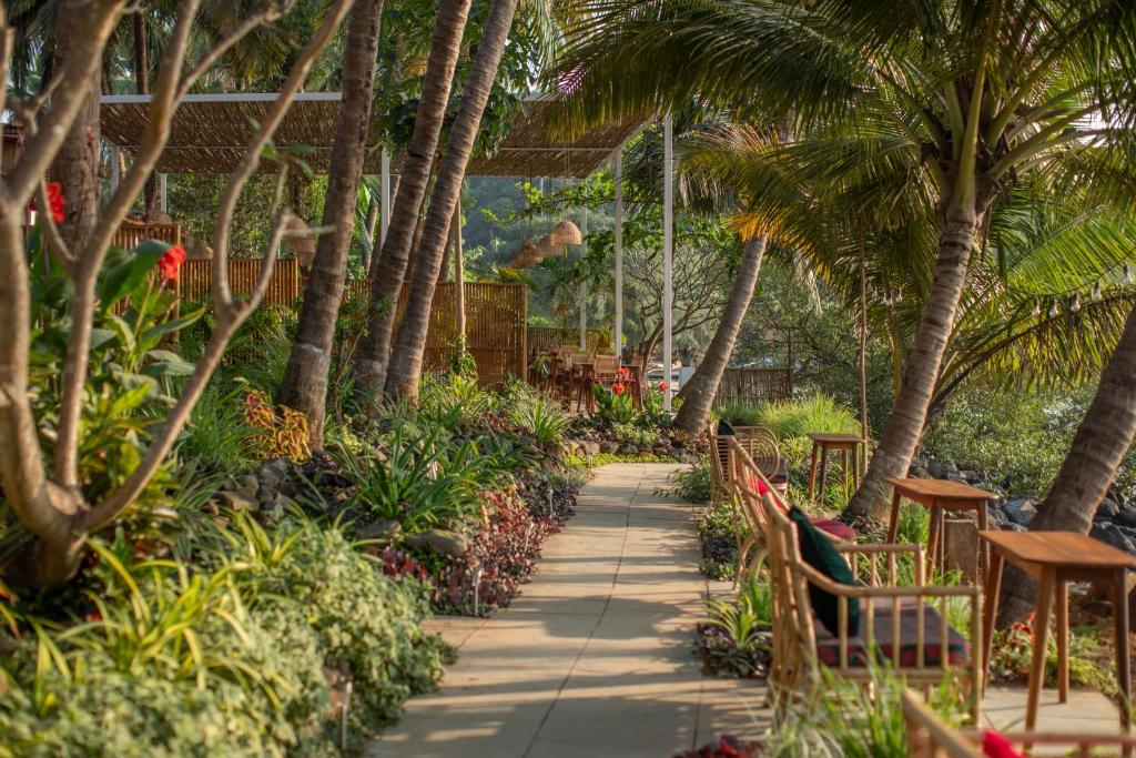 een loopbrug met stoelen en palmbomen in een resort bij Casa Jaali in Patnem