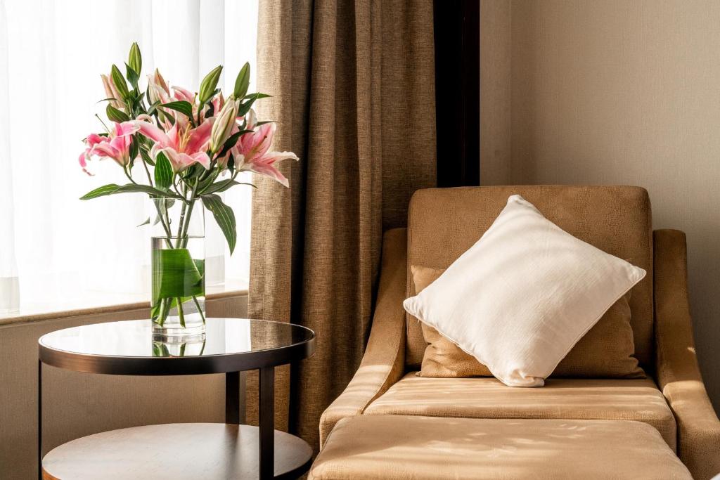 a vase of flowers on a table next to a chair at Crowne Plaza Shanghai by IHG in Shanghai