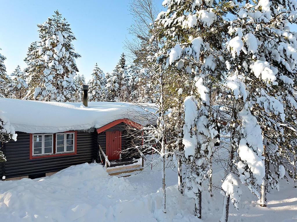a cabin with a red door covered in snow at Björnbyn in Sälen