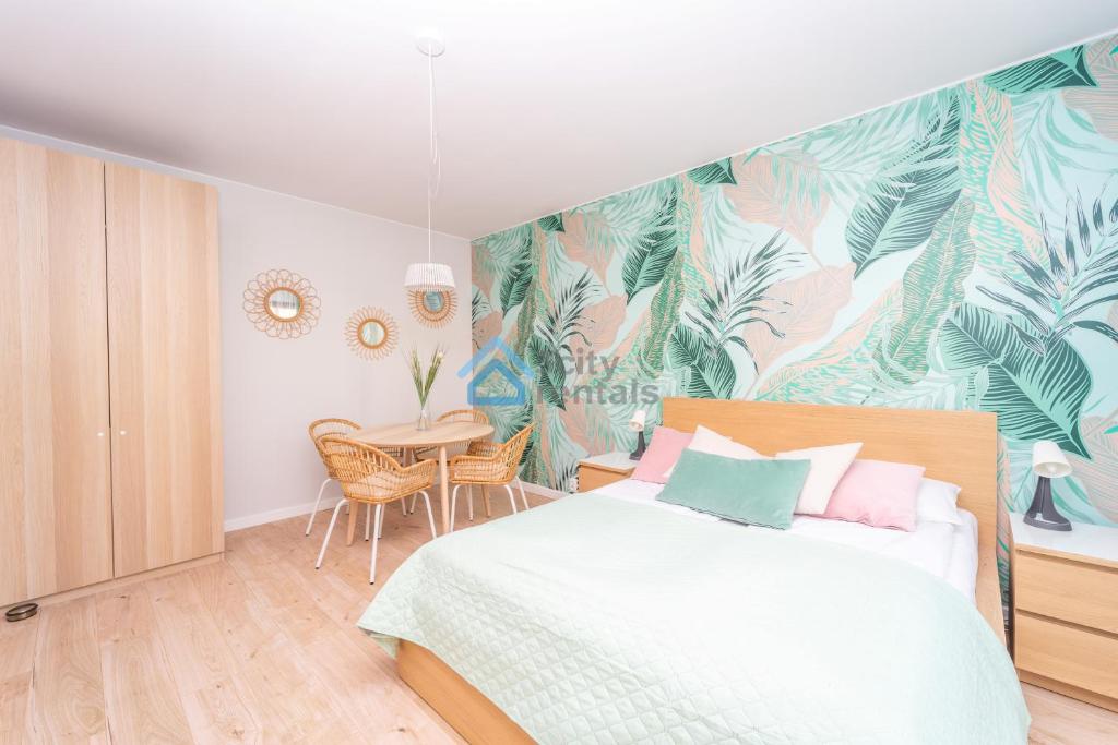 a bedroom with a bed with a tropical wallpaper at Botanika Deluxe Apartment Sopot in Sopot