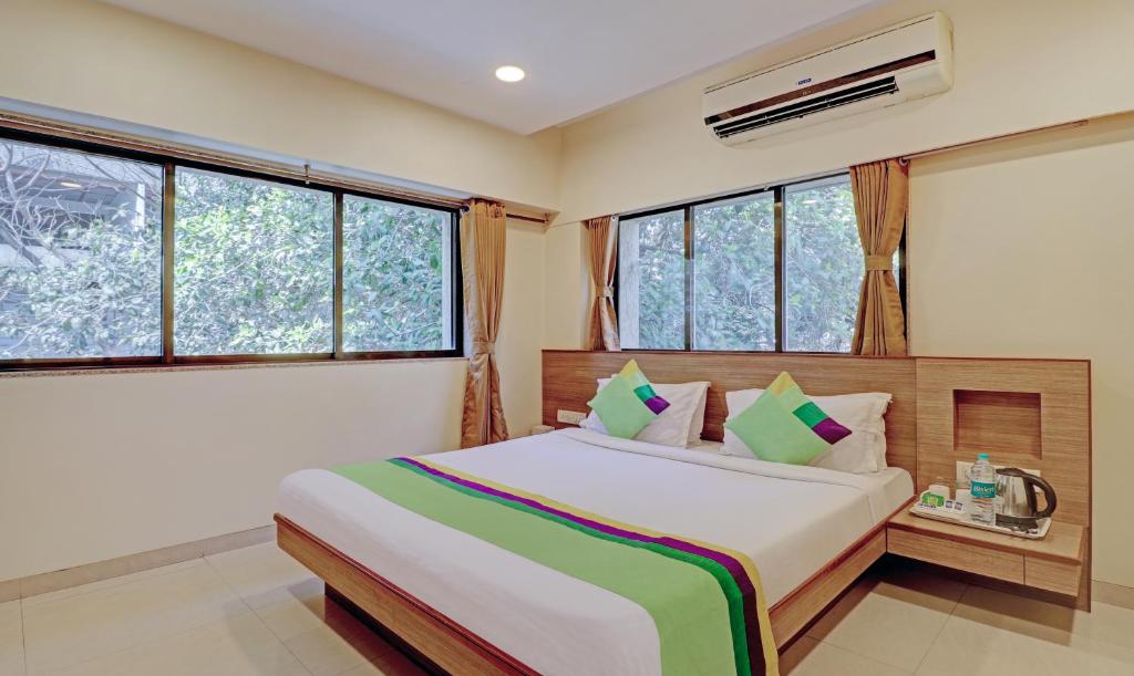 um quarto com uma cama grande e janelas em Treebo Trend Vikrant Residency em Pune