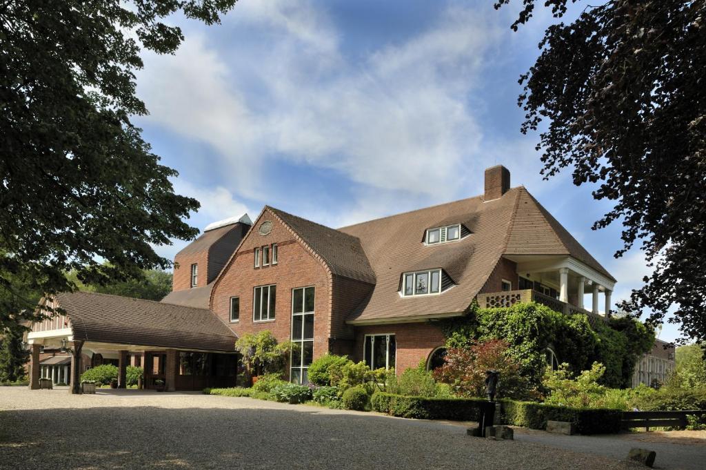 een groot bakstenen huis met een dak bij Landgoed De Wilmersberg in De Lutte