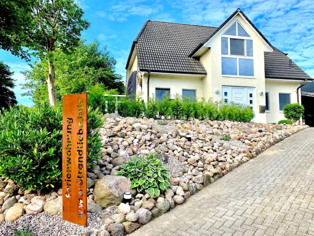ein Haus mit einem Steingarten vor einem Haus in der Unterkunft Wellness & Komfortferienwohnung Strandliebe mit Sauna, Terrasse, Garten & Balkon, bei Laboe in Lutterbek