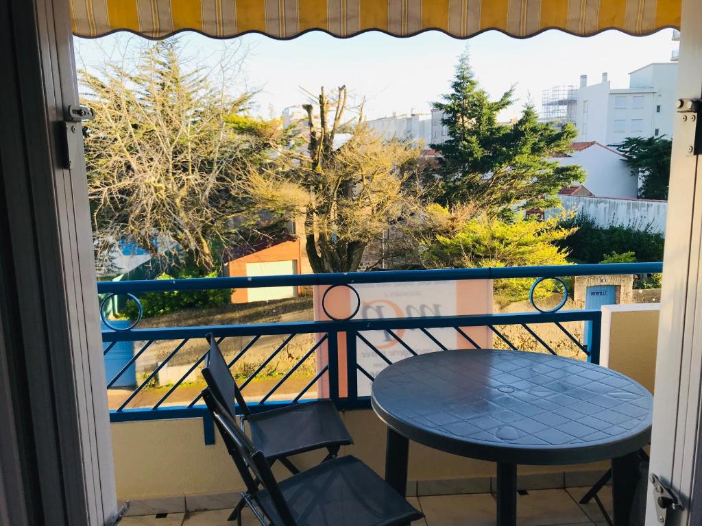 un balcon avec une table, des chaises et une fenêtre dans l'établissement Pied à terre à deux pas de la mer, des commodités, à Saint-Jean-de-Monts