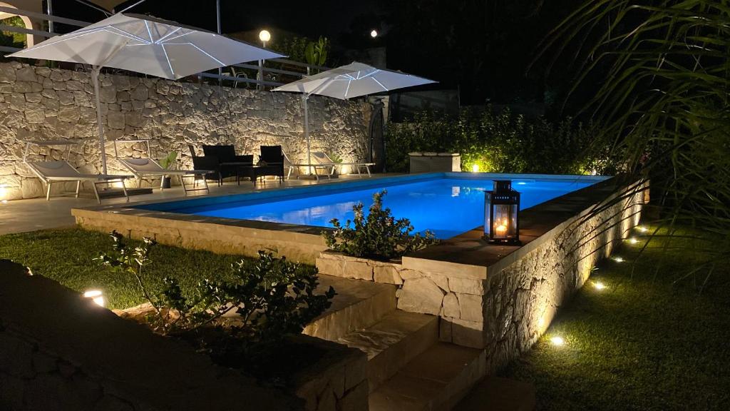 uma piscina num quintal à noite com luzes em Villa Lucia With Salt Pool em Fontane Bianche