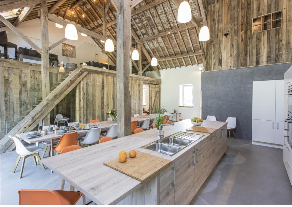 an industrial kitchen with wooden walls and tables and chairs at La Grange de Victor in Léglise