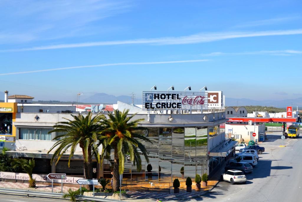 a hotel with palm trees in front of a street at Hotel El Cruce in Moraleda de Zafayona