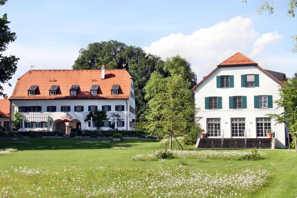 una grande casa bianca con tetto rosso di Hotel Aiterbach am Chiemsee a Rimsting