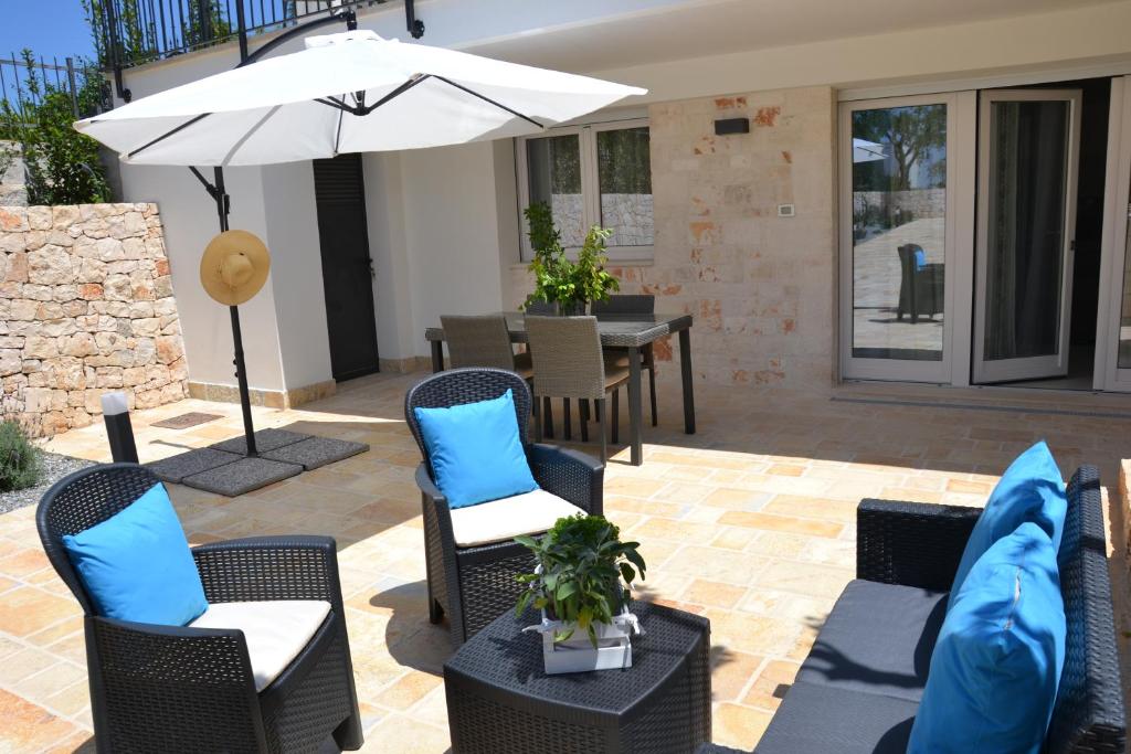 eine Terrasse mit Stühlen, einem Sonnenschirm und einem Tisch in der Unterkunft Il Crepuscolo Apartment - Villaggio di Mary in Locorotondo