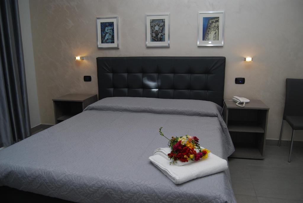 a bedroom with a bed with a bouquet of flowers on it at La Dimora in Catania