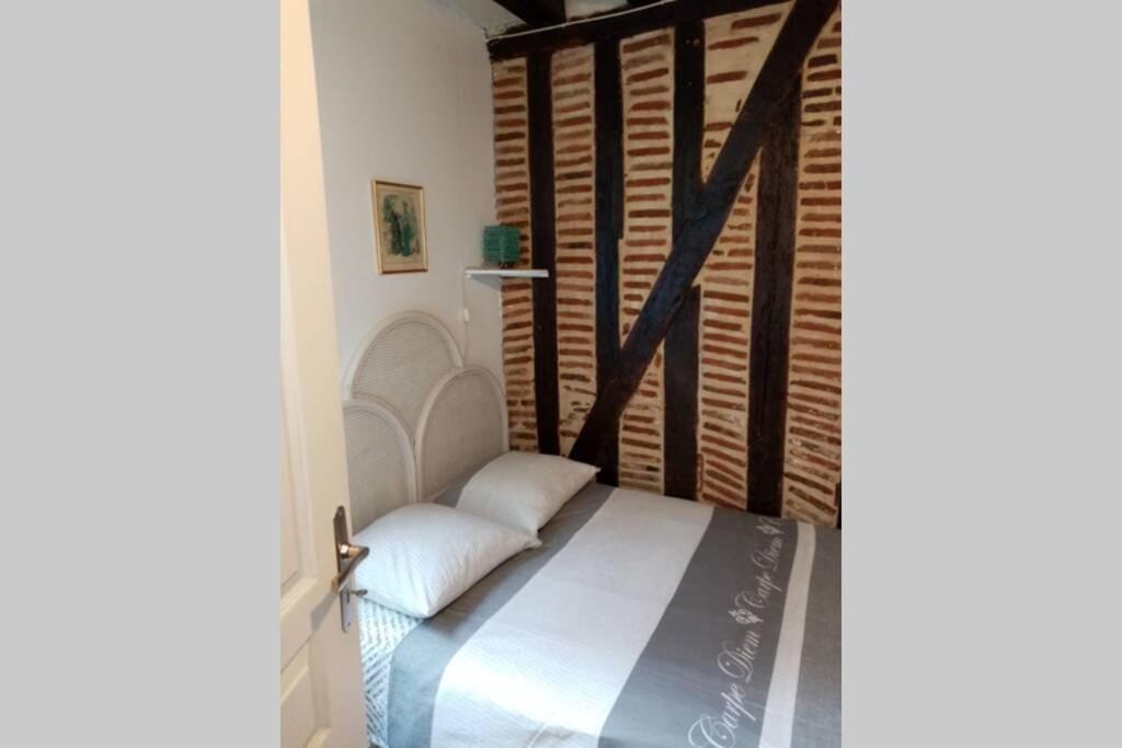 um quarto com uma cama com lençóis brancos e almofadas em Appartement deux pièces - coeur de ville quartier cathédrale em Tours