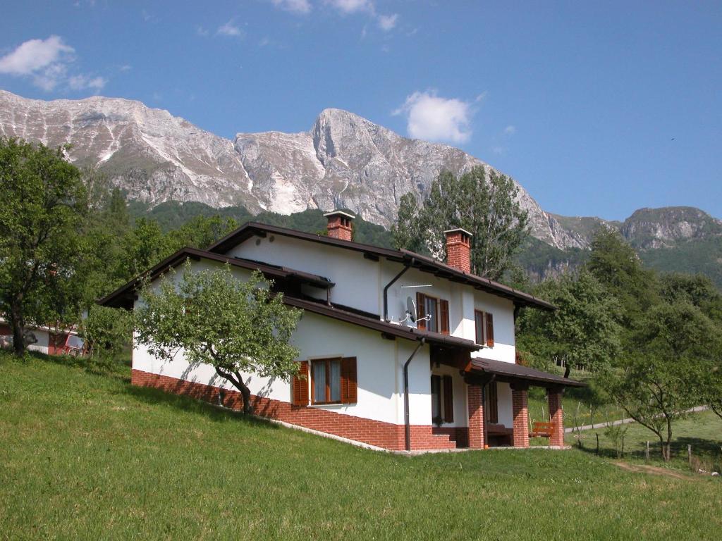 a house on a hill with mountains in the background at Apartments Ivančič in Kobarid