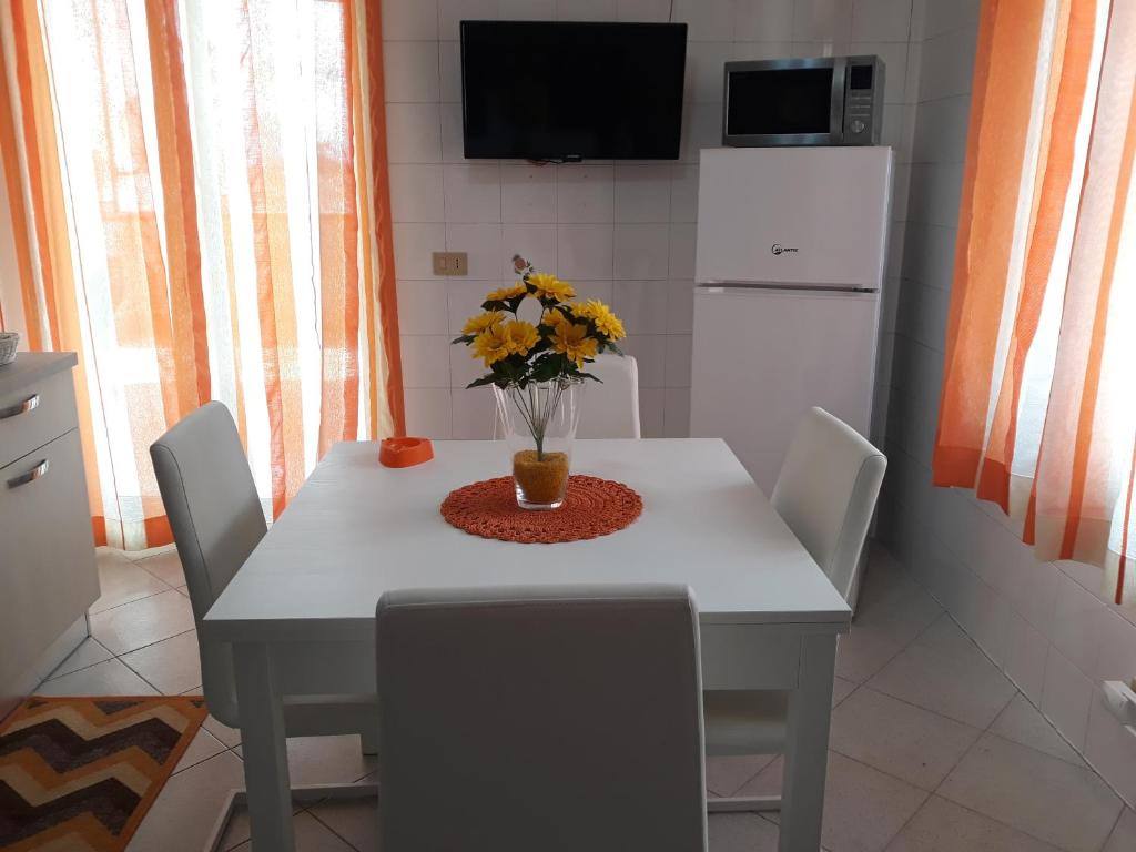 a white table with chairs and a vase of flowers on it at casaLiuccia in Mondello