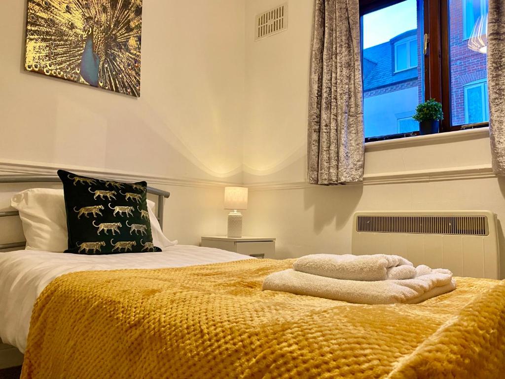 una camera da letto con un letto con una coperta gialla e una finestra di EasyRest Spalding - 4 Beds & Free Parking - Central & Modern Open Plan Apartment - Convenient Location a Spalding