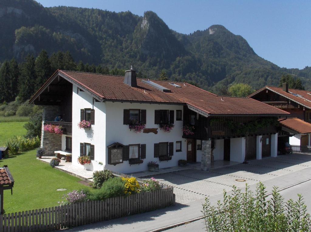 une maison blanche avec des montagnes en arrière-plan dans l'établissement Haus Moosbach, à Oberwössen