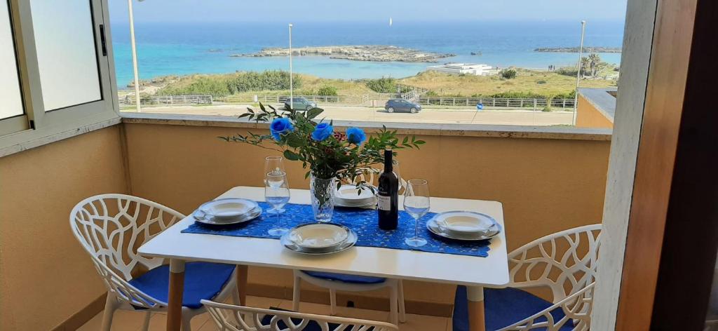 uma mesa branca com um vaso de flores em Bilocale Punta Rosa - Fronte Spiaggia em Otranto