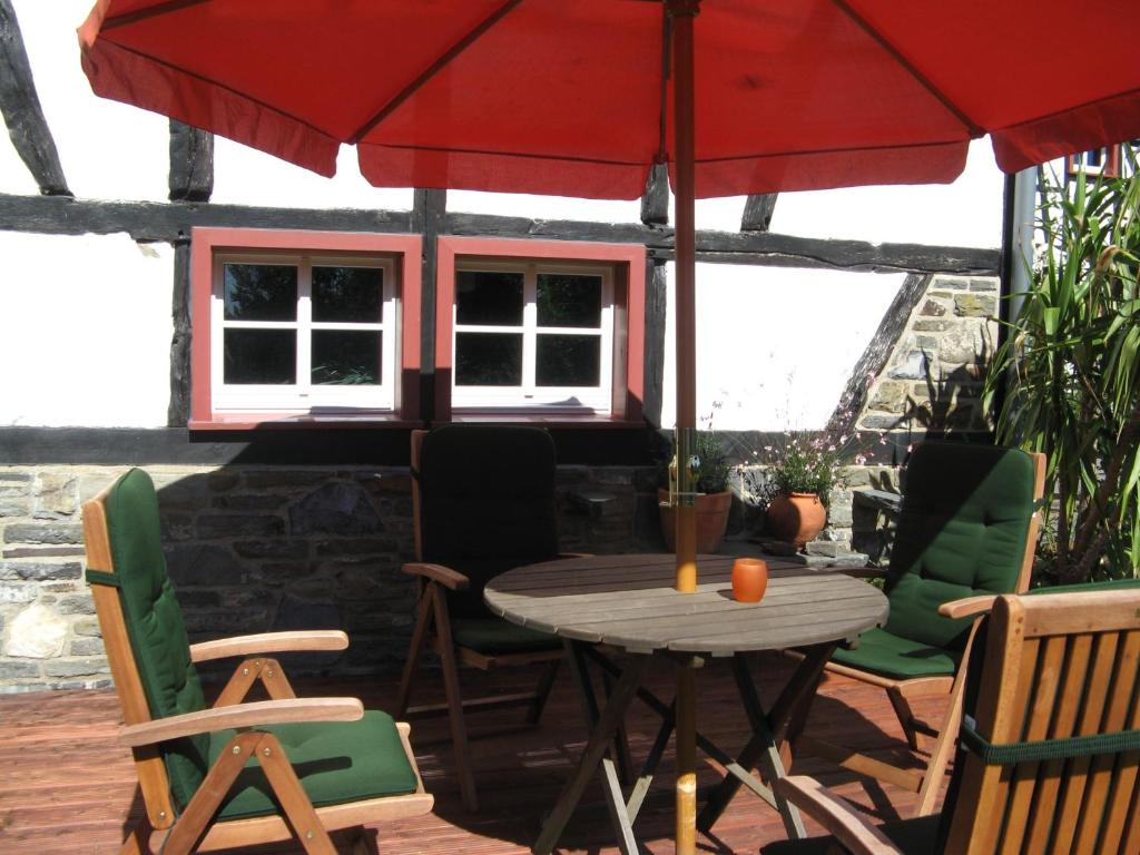 eine Terrasse mit einem Tisch, Stühlen und einem Sonnenschirm in der Unterkunft Lehmlounge in Monschau