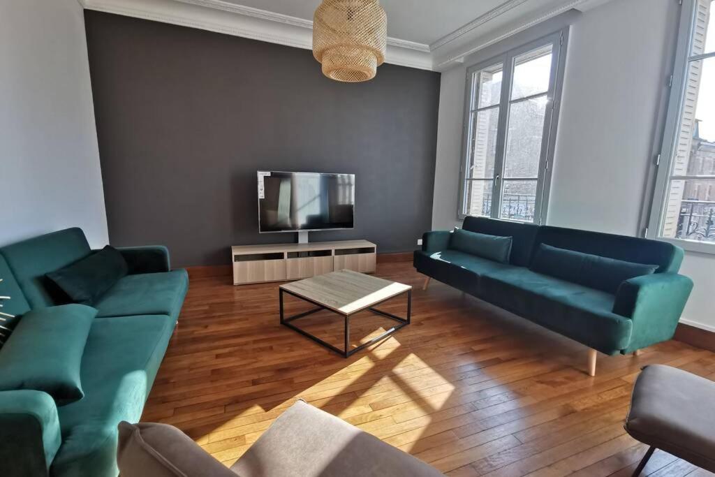 a living room with two green couches and a television at La Maison de Timothée 11 couchages in Reims