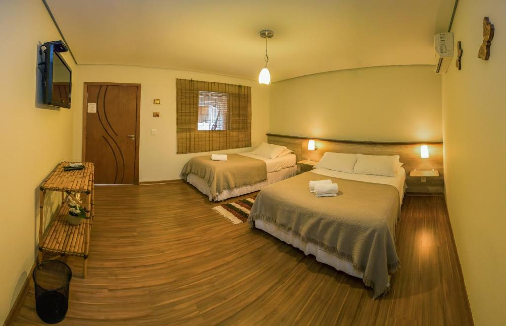 a hotel room with two beds and a television at Pousada Vento Sul in Chapada dos Guimarães