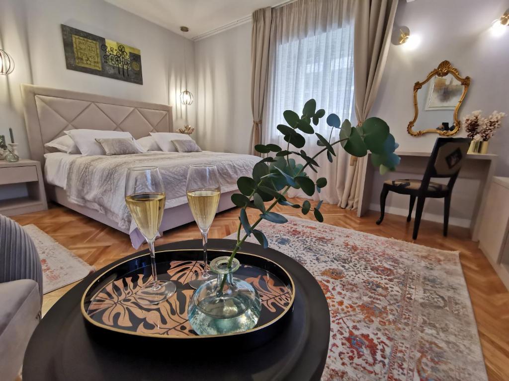 Merla Art & Luxury Rooms في سبليت: غرفة نوم مع سرير وطاولة مع كأسين من النبيذ