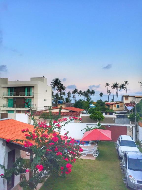 a view of a resort with pink flowers and cars at Casa do Francês Temporada in Marechal Deodoro
