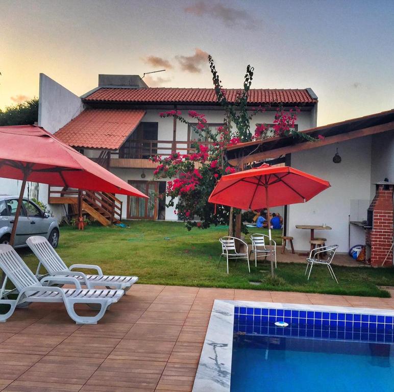 ein Haus mit Stühlen und Sonnenschirmen sowie einem Pool in der Unterkunft Casa do Francês Temporada in Maceió