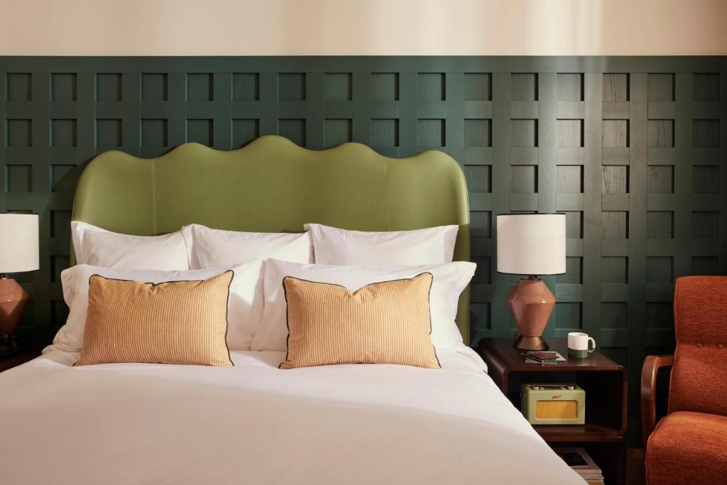a bedroom with a large bed with a green headboard at The Hoxton, Rome in Rome