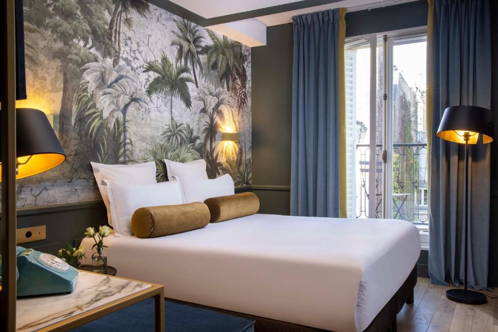 a bedroom with a large bed and a large window at Les Jardins Du Luxembourg in Paris