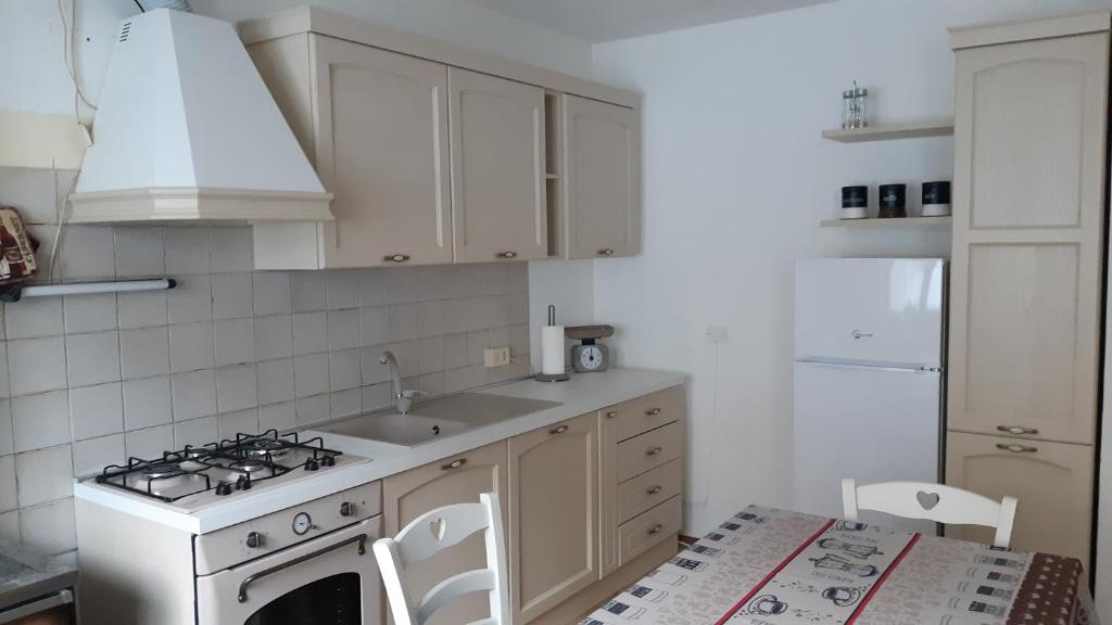 a white kitchen with a stove and a sink at CASA MASCIA in Cencenighe