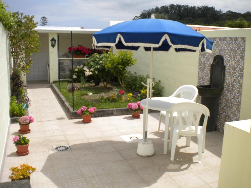 eine Terrasse mit einem Tisch und einem blauen Sonnenschirm in der Unterkunft Casa Nuno e Lorena - Casa completa e Localização ideal in Ponta Delgada